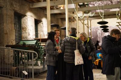 A group talks beside old jute-making machinery